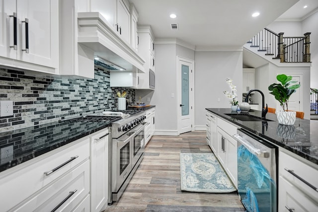 kitchen with white cabinets, sink, appliances with stainless steel finishes, and dark stone counters