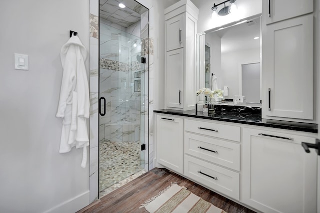 bathroom with hardwood / wood-style flooring, vanity, and a shower with door