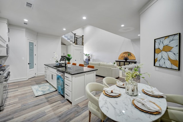 kitchen with a kitchen island with sink, dark stone counters, white cabinets, sink, and stainless steel appliances