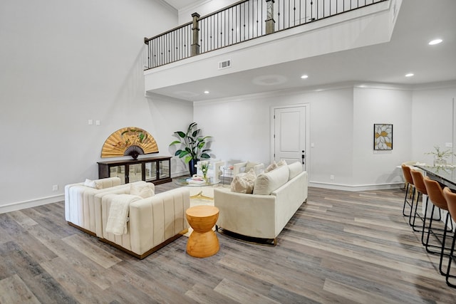 living room featuring crown molding, hardwood / wood-style floors, and a high ceiling