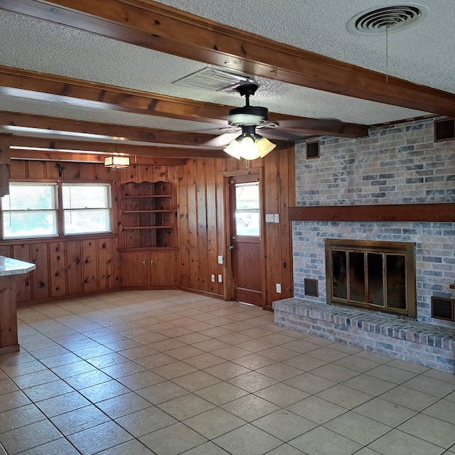 unfurnished living room with a textured ceiling, a healthy amount of sunlight, and wood walls