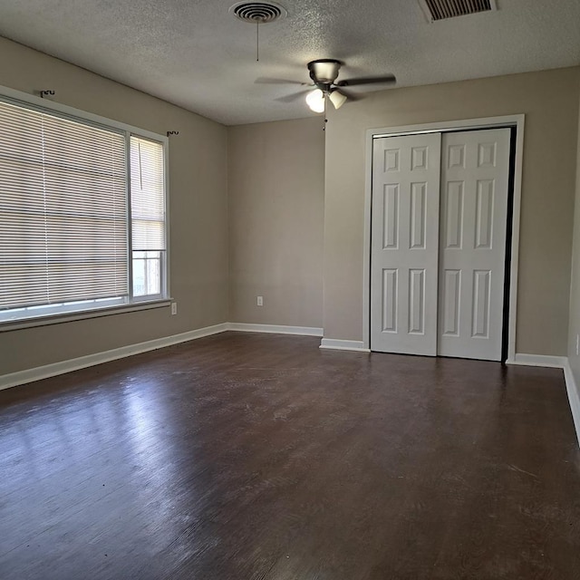 unfurnished bedroom with a textured ceiling, ceiling fan, and dark wood-type flooring