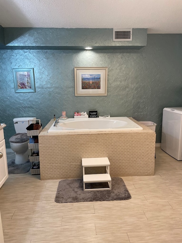 2804 33rd St, Snyder, TX 79549 - bathroom with toilet, a garden tub, washer / clothes dryer, wood finished floors, and vanity