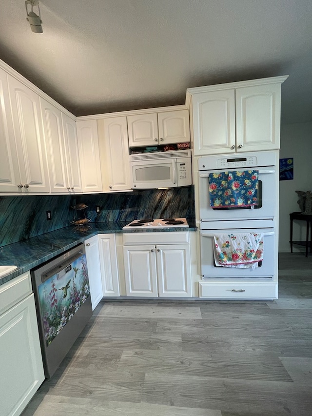 2804 33rd St, Snyder, TX 79549 - kitchen with white appliances, dark countertops, white cabinetry, and light wood-type flooring