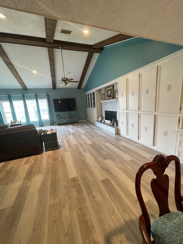2804 33rd St, Snyder, TX 79549 - living room with ceiling fan, a fireplace, light wood-style flooring, a textured ceiling, and a decorative wall