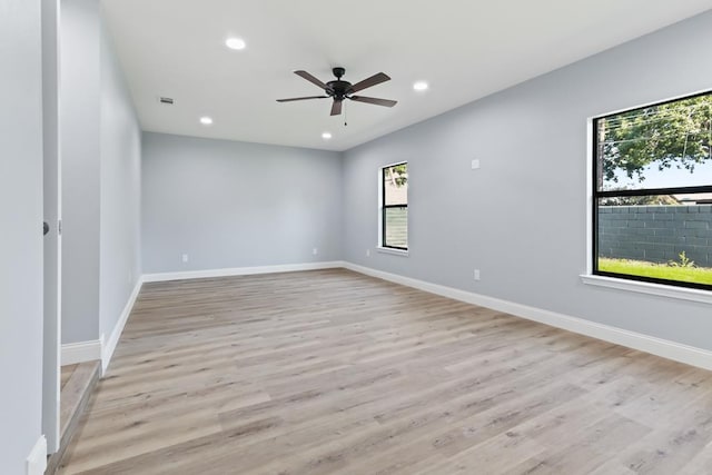 spare room featuring ceiling fan, a healthy amount of sunlight, and light wood-type flooring