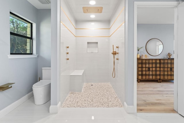 bathroom featuring a tile shower, toilet, and hardwood / wood-style flooring