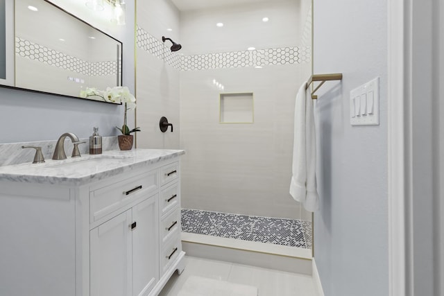 bathroom featuring a tile shower, tile patterned flooring, and vanity