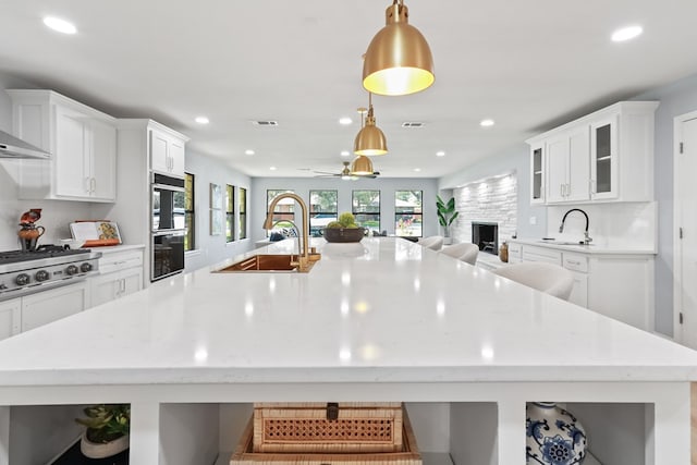 kitchen featuring a breakfast bar, stainless steel gas cooktop, sink, white cabinetry, and hanging light fixtures