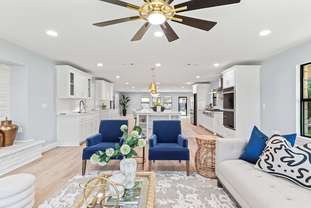 living room with light hardwood / wood-style flooring, ceiling fan, and sink