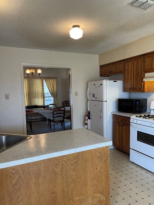 4400 Palmer Dr, Midland, TX 79705 - kitchen featuring white appliances, light flooring, a chandelier, a textured ceiling, and under cabinet range hood