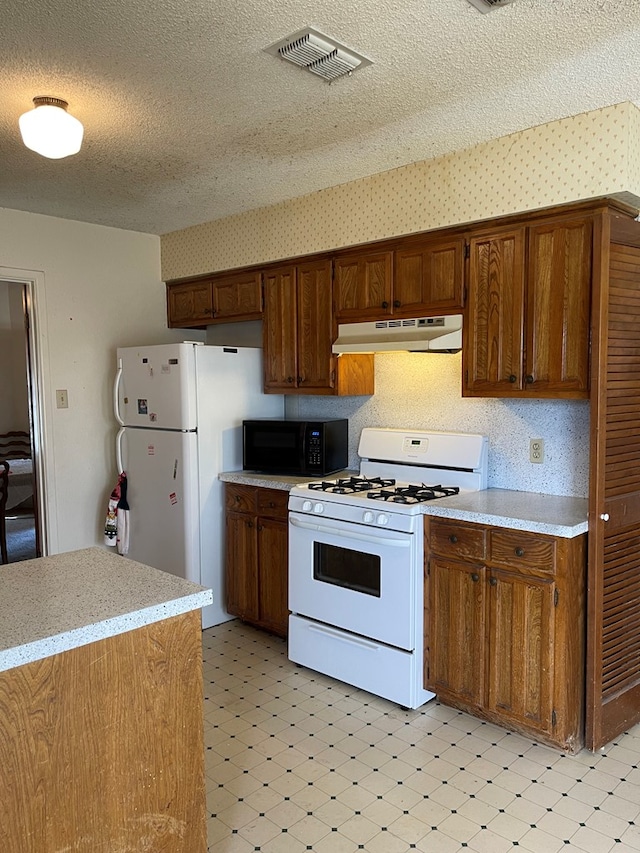 4400 Palmer Dr, Midland, TX 79705 - kitchen featuring white appliances, under cabinet range hood, light floors, light countertops, and a textured ceiling