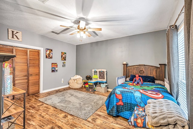 bedroom featuring visible vents, a ceiling fan, wood finished floors, a textured ceiling, and a closet