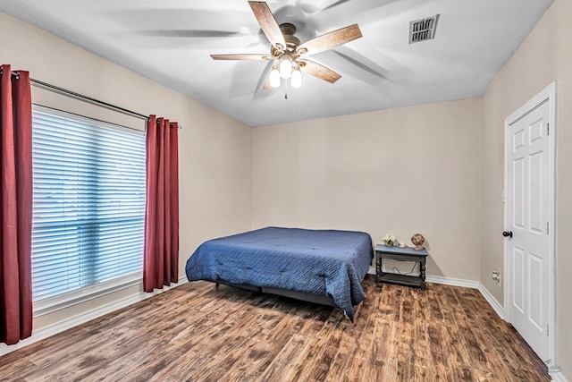 bedroom featuring dark wood-style floors, ceiling fan, visible vents, and baseboards