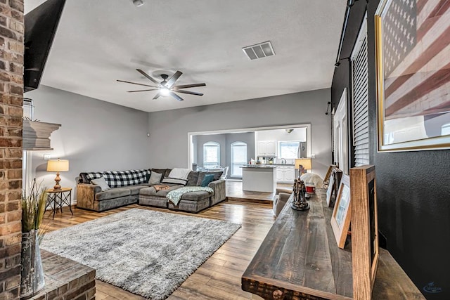 living area with light wood-type flooring, ceiling fan, and visible vents