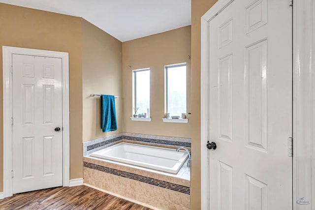 bathroom with wood finished floors and a garden tub