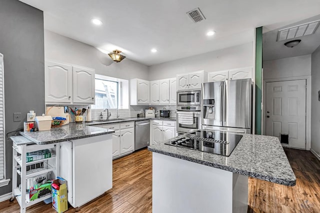 kitchen featuring a peninsula, white cabinetry, visible vents, and appliances with stainless steel finishes