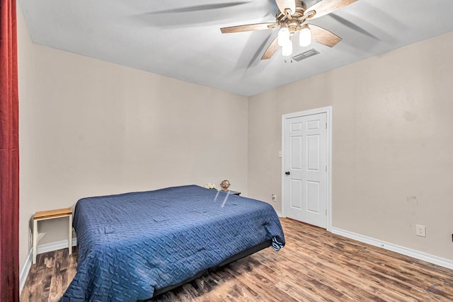 bedroom featuring baseboards, visible vents, ceiling fan, and wood finished floors