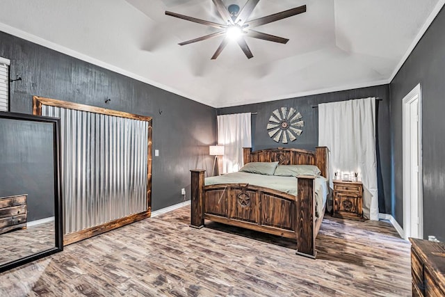 bedroom with ceiling fan, wood finished floors, baseboards, vaulted ceiling, and crown molding