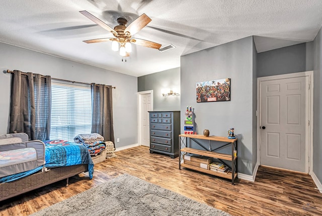 bedroom with visible vents, baseboards, and wood finished floors