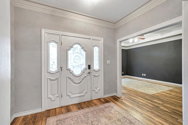 foyer with ornamental molding, plenty of natural light, baseboards, and wood finished floors