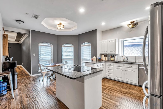 kitchen featuring visible vents, freestanding refrigerator, a peninsula, a tray ceiling, and white cabinetry