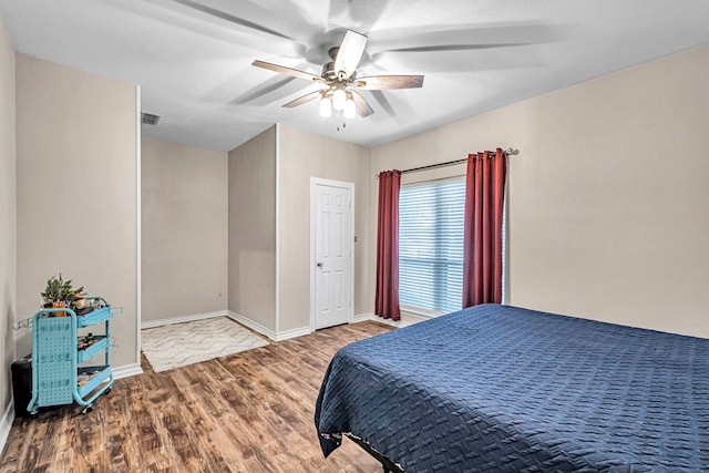 bedroom with visible vents, baseboards, ceiling fan, and wood finished floors