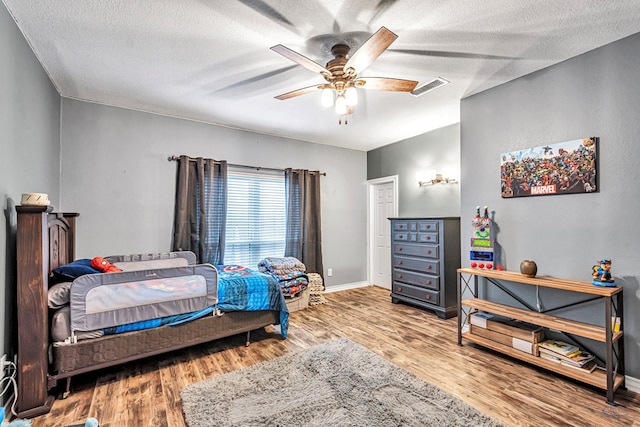 bedroom featuring a textured ceiling, wood finished floors, visible vents, and baseboards