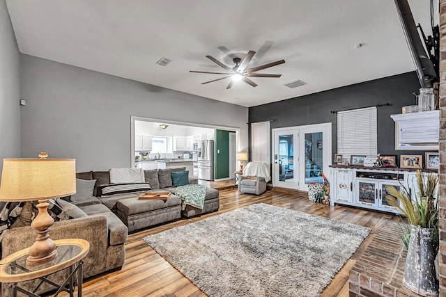 living area with light wood-type flooring, french doors, visible vents, and ceiling fan