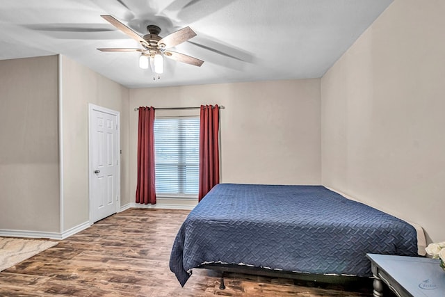 bedroom with ceiling fan, wood finished floors, and baseboards