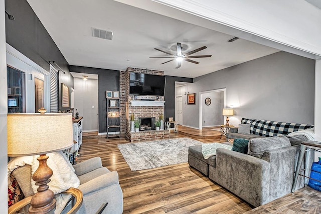 living area with baseboards, visible vents, ceiling fan, wood finished floors, and a fireplace