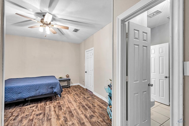 bedroom featuring a ceiling fan, wood finished floors, visible vents, and baseboards