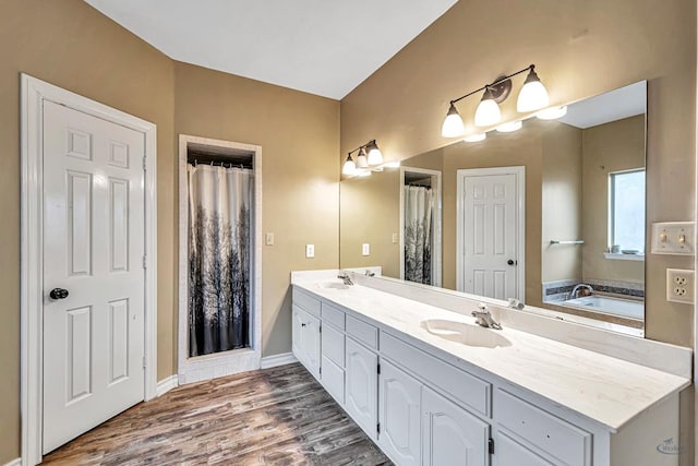 full bathroom with double vanity, a sink, baseboards, and wood finished floors