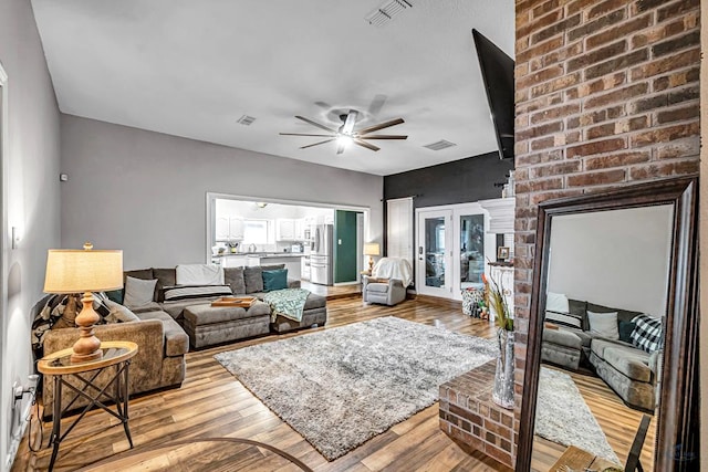 living area featuring visible vents, ceiling fan, and light wood finished floors