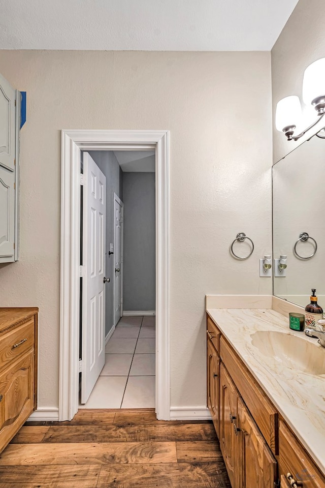 bathroom with a chandelier, vanity, baseboards, and wood finished floors