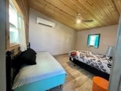 bedroom featuring wood ceiling, vaulted ceiling, a wall mounted AC, ceiling fan, and light hardwood / wood-style flooring