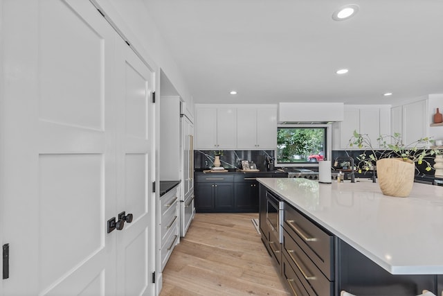 1611 W Tennessee Ave, Midland, TX 79701 - kitchen with light wood-type flooring, white cabinets, a center island, backsplash, and recessed lighting