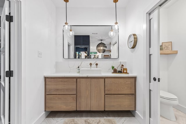 1611 W Tennessee Ave, Midland, TX 79701 - bathroom with vanity, toilet, baseboards, and tasteful backsplash