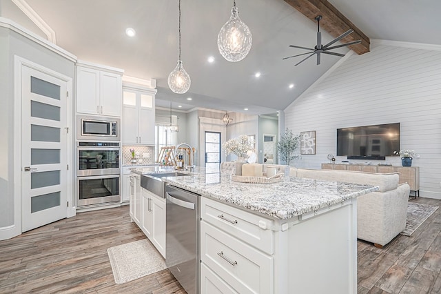 kitchen with a center island with sink, stainless steel appliances, open floor plan, white cabinets, and a sink