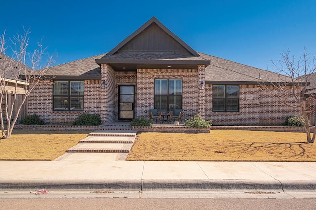 view of front of house with a shingled roof and brick siding