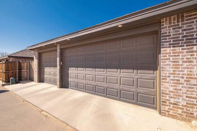 garage featuring driveway and fence