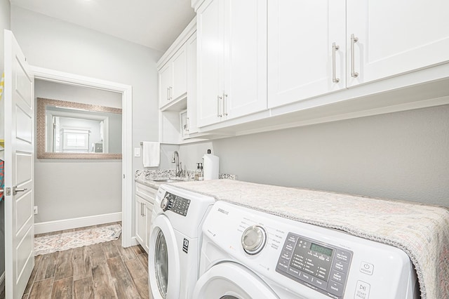 washroom with dark wood-style flooring, cabinet space, a sink, washer and dryer, and baseboards