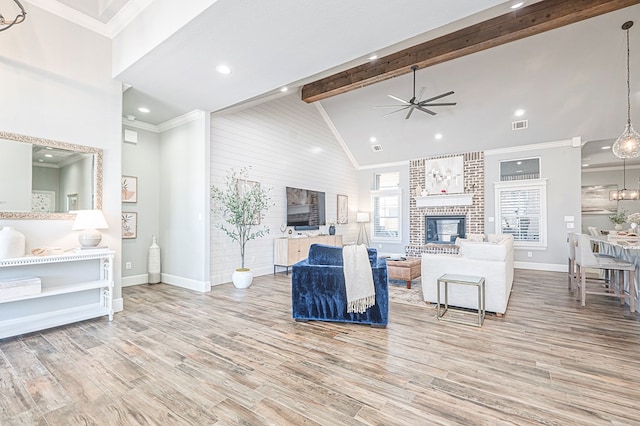 living area with high vaulted ceiling, light wood-style floors, a fireplace, and beamed ceiling