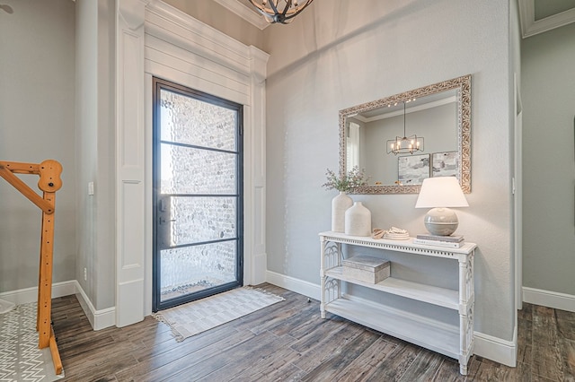 entrance foyer with baseboards, ornamental molding, a notable chandelier, and wood finished floors