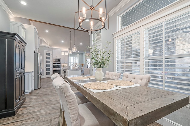 dining space with a high ceiling, crown molding, light wood-style floors, a notable chandelier, and recessed lighting