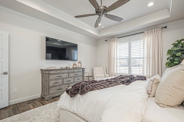 bedroom featuring dark wood-type flooring, a tray ceiling, crown molding, and baseboards