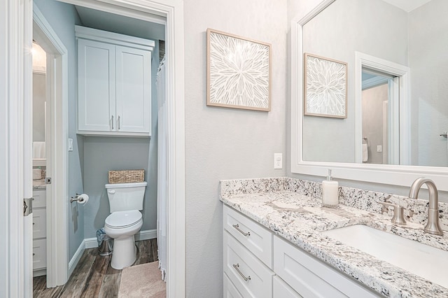 bathroom with toilet, baseboards, wood finished floors, and vanity