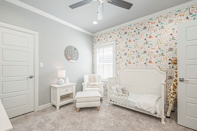 bedroom featuring ornamental molding, a ceiling fan, light carpet, a crib, and baseboards