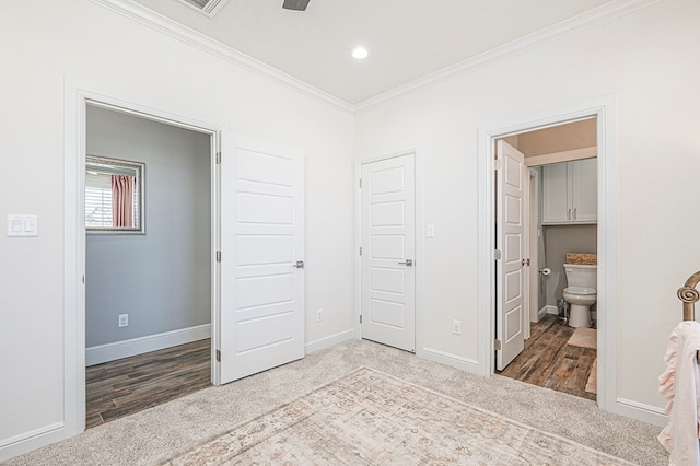 carpeted bedroom featuring baseboards, ensuite bath, and crown molding