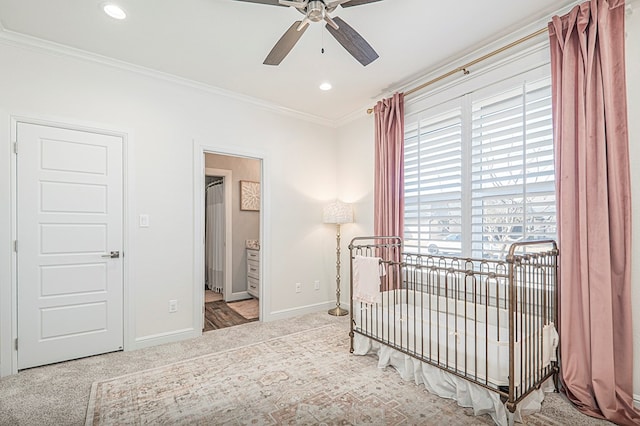 bedroom with light carpet, a nursery area, baseboards, and ornamental molding